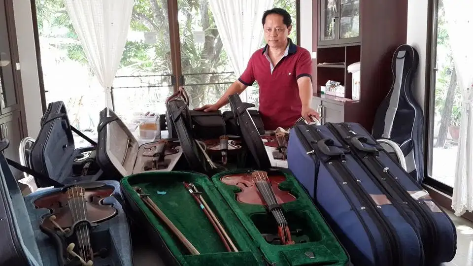 คุณขวัญชัยเลือกและทดลองเสียงไวโอลินภายในร้าน